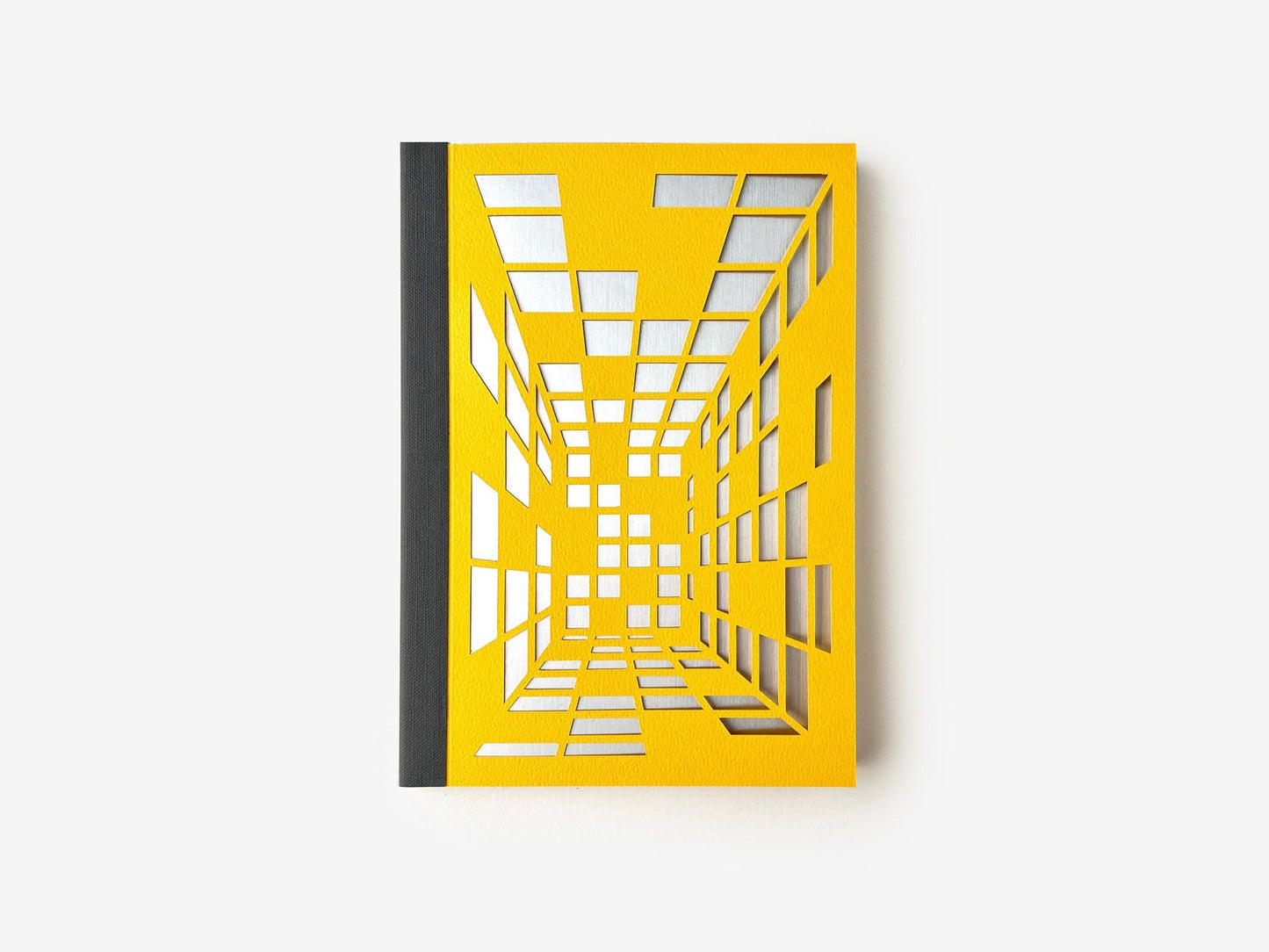 A sketchbook with a yellow cover featuring a geometric isometric design, indicating a focus on perspective layout, suitable for architects and designers.